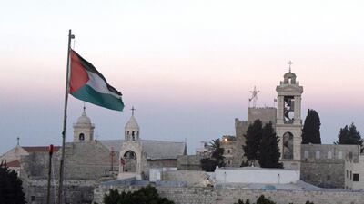 The Palestinian flag flutters in front of the Church of the Nativity, the traditional birthplace of Jesus Christ, in the biblical West Bank town of Bethlehem. MUSA AL SHAER / AFP
