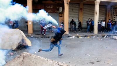 An Iraqi protester runs to throw tear gas canister back toward riot police forces during clashes with anti-riot police forces at the Al Rasheed street in central Baghdad. EPA