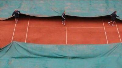 Stadium employees cover centre court as the men's final match between Rafael Nadal and Novak Djokovic was suspended because of the rain at Roland Garros on Sunday. David Vincent / AP Photo