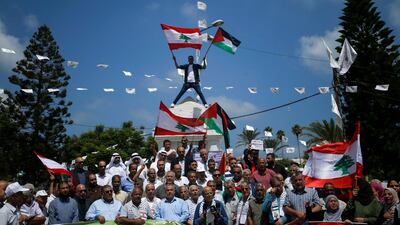 Palestinians hold Lebanese flags as they gather to show solidarity with the Lebanese people following the huge explosions in Beirut's port area, in Gaza City, on August 6, 2020. / AFP / MOHAMMED ABED