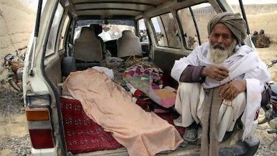An elderly man in Kandahar province, south of Kabul, sits next to the covered body of a person allegedly killed by a US soldier on Sunday. The serviceman walked out of a base and started shooting civilians, according to villagers and Afghan and Nato officials.