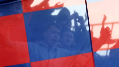 Fans seen through a flag as they watch the match. EPA