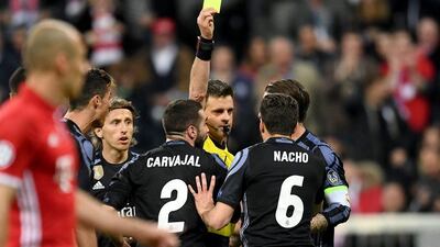 Referee Nicola Rizzoli shows Nacho of Real Madrid a yellow card. Lennart Preiss / Getty Images