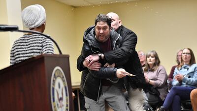 A man is tackled after spraying an unknown substance at US Representative Ilhan Omar, left, in a town hall in Minneapolis, Minnesota. AFP