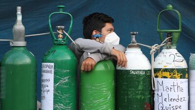 A youth rests on his empty oxygen cylinder waiting for a refill shop to open in the San Juan de Lurigancho neighborhood of Lima, Peru. AP Photo