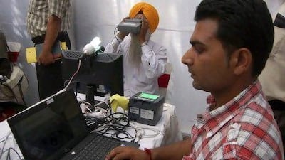 An Indian Sikh (centre) looks through an optical biometric reader, which scans an individual's iris patterns, during registration for an Aadhaar card in Amritsar.