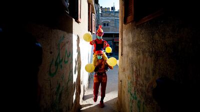Clowns, wearing surgical masks due to the COVID-19 coronavirus pandemic, walk with balloons in al-Nusairat refugee camp in the central Gaza Strip as they celebrate with children the start of Ramadan. AFP