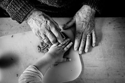 Ana Backhaus received third place for a photograph showing older hands guiding a child through the process of preparing dough. Photo: Ana Backhaus