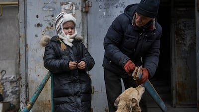 Sasha and her grandfather stand outside their home in Bakhmut. AP