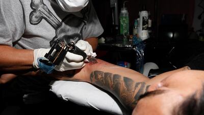 A tattoo artist inks a portrait of Martin Luther King on a client. Jeffrey E Biteng / The National