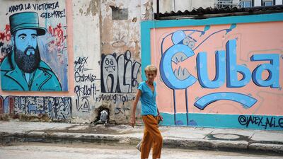 An elderly woman walks along a street next to street art in Havana. All photos by Yamil Lage / AFP Photo