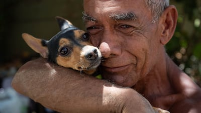 A man hugs his dog after it was rescued from the rubble of a building in La Guaira. EPA