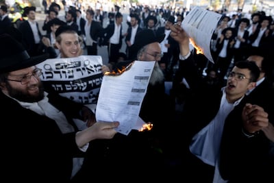 Ultra-Orthodox Jewish men burn conscription orders as they block a main motorway during a protest against drafting to the Israeli army. Getty Images
