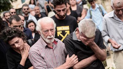 Mr Khalifa's brother (left) mourns during the funeral of the distinguished writer