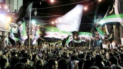 Syrians wave revolutionary flags and chant slogans at a night protest against President Bashar Assad in Damascus on Monday.