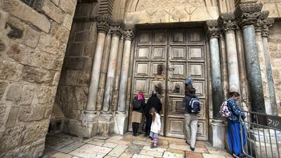 Christian pilgrims pray by the closed wooden doors of the Church of the Holy Sepulchre.