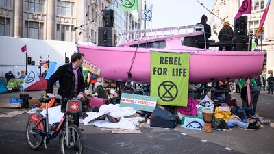 A man pushes his bicycle past the Extinction Rebellion boat in the centre of Oxford Cricus in London. Now in the third day of action, the environmental campaign group has blocked a number of key junctions in central London, in a bid to highlight the ongoing ecological crisis. Getty Images