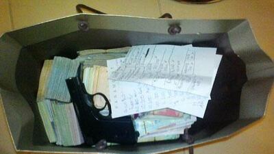 Dubai Police release a photo of the gun and money stolen from a reported robbery at Redha al Ansari’s branch in Motorcity on Sunday.