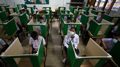Students in a protective gear are seated at partitioned desks at the Samkhok School in Pathum Thani, outside Bangkok. AP Photo