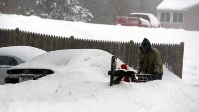 A man uses a snowblower to try to dig out a buried car several hours into the blizzard which struck the Northeastern US in Franklin, Massachusetts. Matt Campbell/EPA