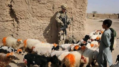 A US soldier stands guard as a boy and his sheep pass in Afghanistan's Kandahar province. Romeo Gacad / AFP