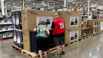 A sales associate helps a shopper at a Costco. Inflation in the US edged up in July after 12 straight months of declines. AP
