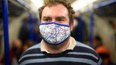 A transport enthusiast wears a London Underground map facemask as he travels on the first train leaving Battersea Power Station.