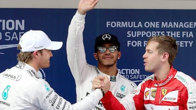 Lewis Hamilton, centre, salutes the crowd after topping qualifying for the Chinese Grand Prix. Nico Rosberg, left, and Sebastian Vettel, right, will start second and third respectively. Wu Hong / EPA