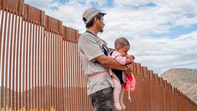A migrant stands with his daughter while waiting to be apprehended by US Customs and Border officers in Ruby, Arizona. Getty Images / AFP