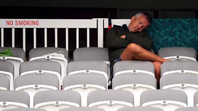 A fan in the stands waits for the start of play as the rain continues to fall. Mike Egerton / PA Wire