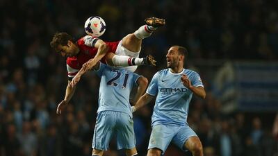 Arsenal’s Mathieu Flamini, left, challenges Manchester City’s David Silva, centre, as Pablo Zabaleta watches during their English Premier League soccer match at The Emirates Stadium in London on March 29, 2014. REUTERS/Eddie Keogh