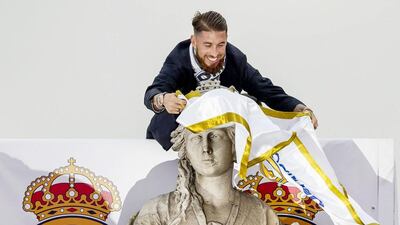 Real Madrid player Sergio Ramos ties a Real Madrid flag around the neck of goddess Cibeles monument as the team arrives at Cibeles square after winning the Champions League final soccer match between Real Madrid and Atletico Madrid, during a celebration parade in Madrid, Sunday, May 29, 2016. Real Madrid won 5-3 on penalties after the match ended 1-1 after extra time. (AP Photo/Daniel Ochoa de Olza)