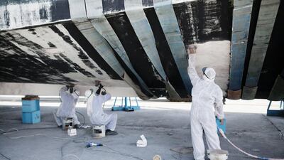 Workers sand off old paint on a yacht at the Gulf Craft factory. Sarah Dea / The National