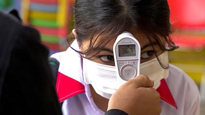 A student from the Sovannaphumi school has her temperature checked in Phnom Penh, Cambodia. Reuters