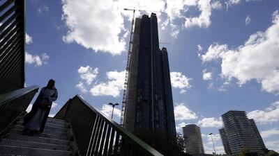 A woman crosses a bridge as an under construction skyscraper is seen in the background in Istanbul. Police have warrants to detain 120 company executives as part of the investigation into last month’s failed coup. Thanassis Stavrakis / AP Photo
