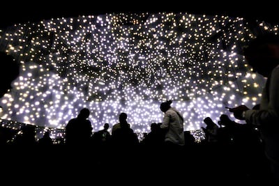 Visitors appear in silhouette against the glowing backdrop of Massless Suns and Dark Suns. Victor Besa / The National