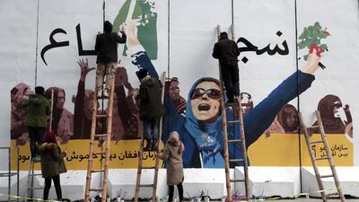 Artists paint a mural on a barrier wall at the Ministry of Women's Affairs to mark International Women's Day in Kabul, Afghanistan. AP