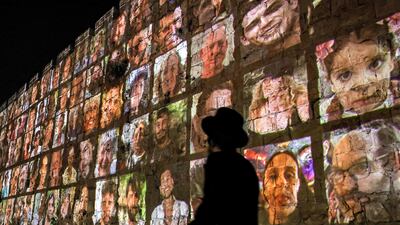 An ultra-Orthodox Jewish man passes the walls of the old city of Jerusalem, on which are projected images of people abducted by Hamas on October 7. AFP