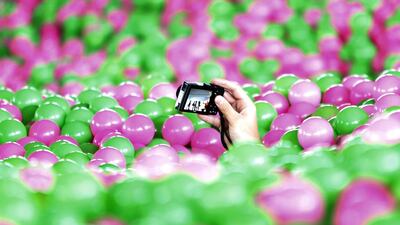 A participant takes pictures with a camera in a swimming pool filled with pink and green plastic balls during a Guinness World Record attempt of the Largest Ball Pit as part of the "Pink October" campaign at Kerry Hotel in Pudong, Shanghai. Aly Song / Reuters