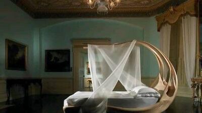 Joseph Walsh's sculptural Enignum canopy bed, made from just two pieces of wood, embraces the user. Courtesy of Nilufar Gallery, www.nilufar.com