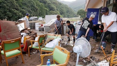 Workers clean a nursing home following a heavy rain in Ashikita town, Kumamoto prefecture. Kyodo News via AP