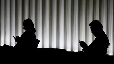 Workers use their smartphones inside an office in the City of London. Heavily indebted UK citizens could be tipped into a financial crisis if the Bank of England goes ahead with interest rate rises this year. Jason Alden/Bloomberg