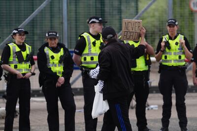 A pro-Palestine campaigner holds up a small placard in front of police officers during a protest outside the Thales factory. PA