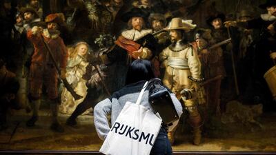 A visitor takes a closer look at Rembrandt's 'The Night Watch' during a press-viewing day at the Rijksmuseum in Amsterdam. AFP