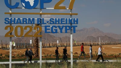 Workers walk past signage promoting this year’s United Nations global summit on climate change, known as COP27, adorns Peace Road, in Sharm el-Sheikh, South Sinai, Egypt. AP Photo