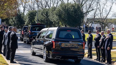 Former and current US Secret Service agents assigned to the Carters stand with their hands over their hearts as the casket departs. AP