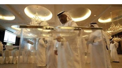 Emirati men check a ballot box for the Federal National Council elections.