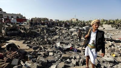 An armed member of the Houthis keeps watch as people gather beside vehicles which were destroyed by a Saudi air strike, in Sanaa, Yemen on March 26, 2015. Yahya Arhab/EPA