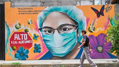 A woman walks past a coronavirus-related mural painted by urban artist Alejandro Bautista Torres, aka Kato, in Mexico City. AFP