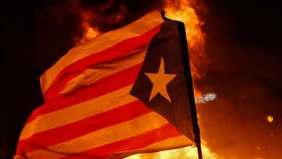 A protester waving a Catalan pro-independence "Estelada" flag stands next to a burning barricade. AFP